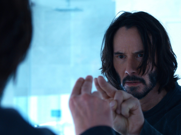 Thomas Anderson (Keanu Reeves) toca o espelho antes de saber que, na verdade, ele é Neo: qual a realidade?