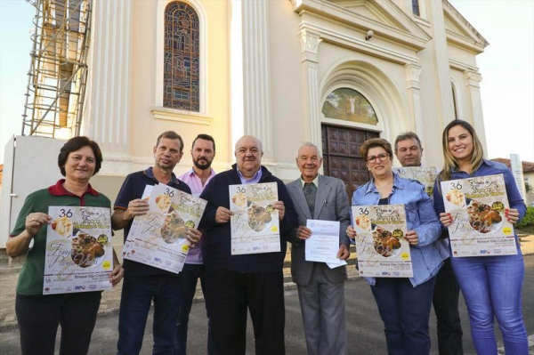 Greca recebe o convite da Festa do frango, polenta e vinho das m\u00e3os do padre Cl\u00e1udio Ambr\u00f3zio (terno cinza), da Par\u00f3quia da Igreja Matriz de S\u00e3o Jos\u00e9 e Santa Felicidade