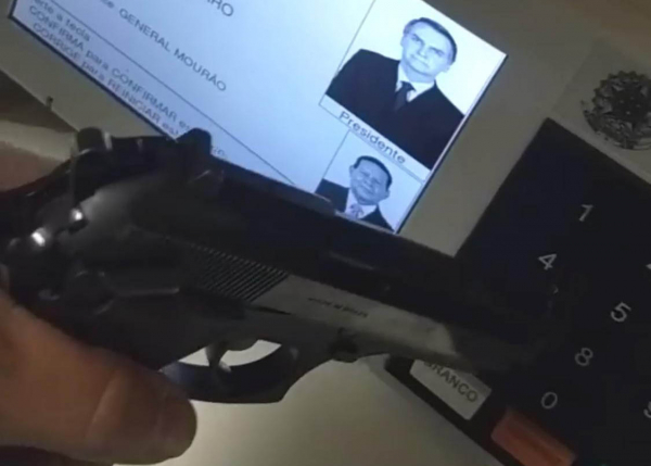 Eleitor exibe arma na urna no domingo
