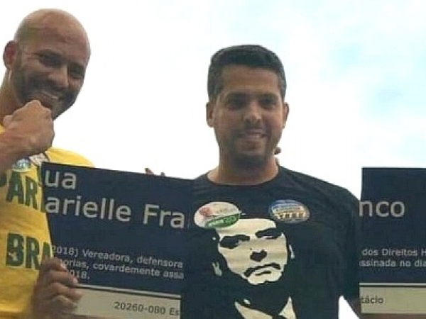 Rodrigo Amorim (à direita) sorri ao exibir placa destruída em homenagem a Marielle