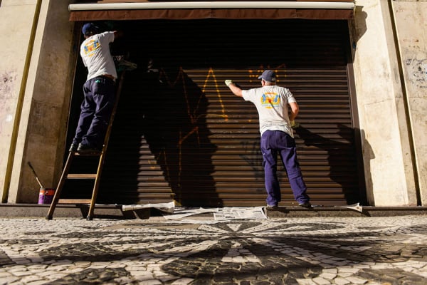 Voluntários despicham fachada de comércio na Rua XV de Novembro