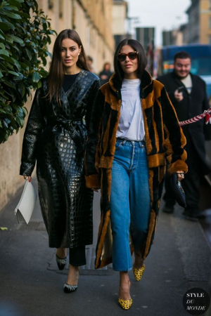 A mesma proposta em duas versões: uma com casaco de couro acinturado, calça de alfaiataria preta e scarpin, e, a outra com jeans e camiseta, casaco de pele fake usado aberto, mais casual, e scarpin