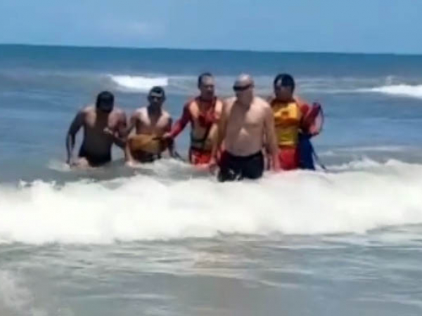 Bombeiros e policial retiram o rapaz do mar de Matinhos